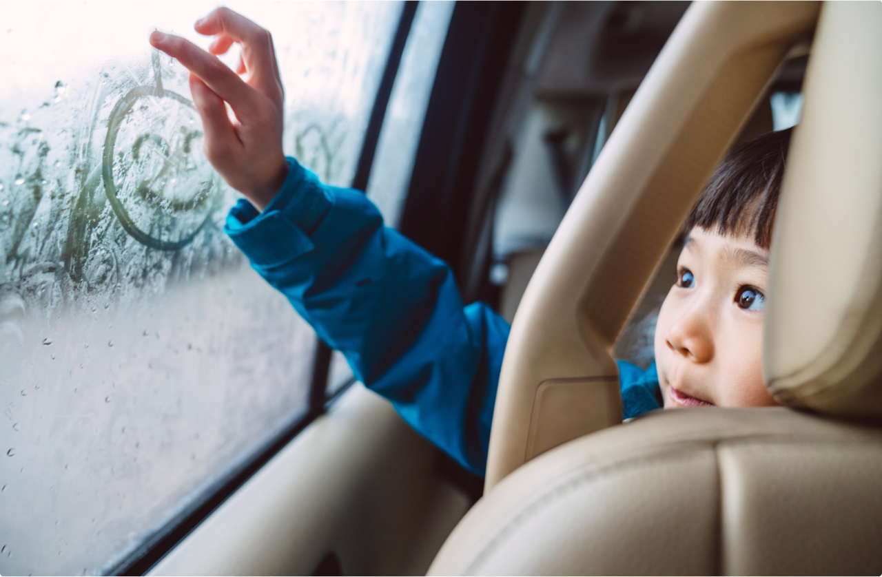 Child drawing on car window